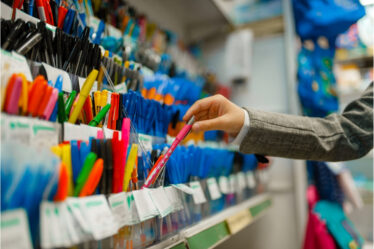 Uma pessoa segurando um lápis em uma loja de material escolar