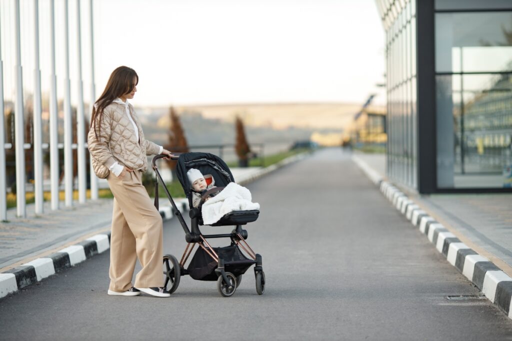 Uma mãe está andando na rua com o seu filho que está em um carrinho de bebê 